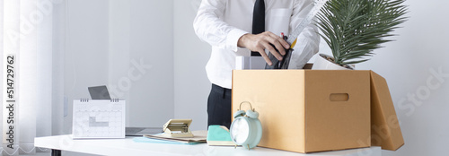 Put the work equipment in the office in a large brown box, Businessmen are keeping work documents and personal belongings due to resignation or being fired, termination of employment. photo