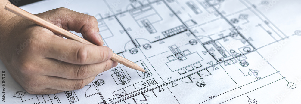 Architectural building design and construction plans with blueprints, Young man was designing a building or architecture with a ruler, pen, pencil, tape measure, architect hat and other equipment. Architectural building design and construction plans with blueprints, Young man was designing a building or architecture with a ruler, pen, pencil, tape measure, architect hat and other equipment.