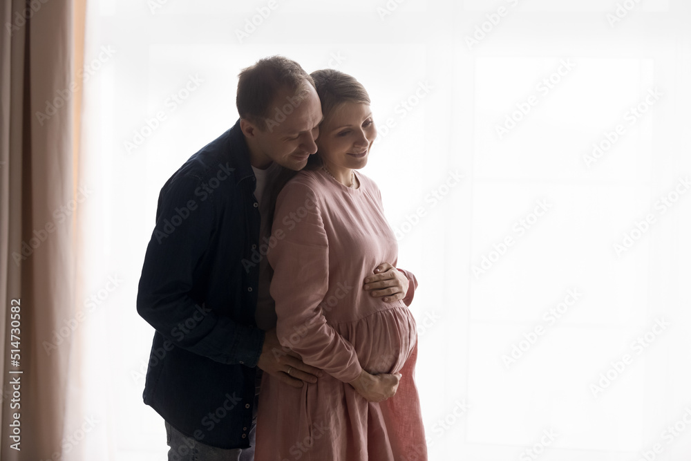 Φωτογραφία On white background pregnant woman enjoy maternity and hugs of loving husband, young 35s couple feeling love to unborn baby, anticipates parenthood looking happy