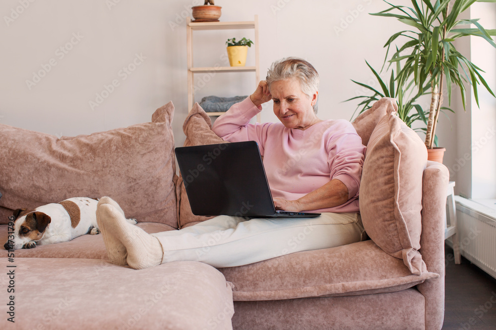 Older smiling 60s woman sitting at home on sofa Older smiling 60s woman sitting at home on sofa
