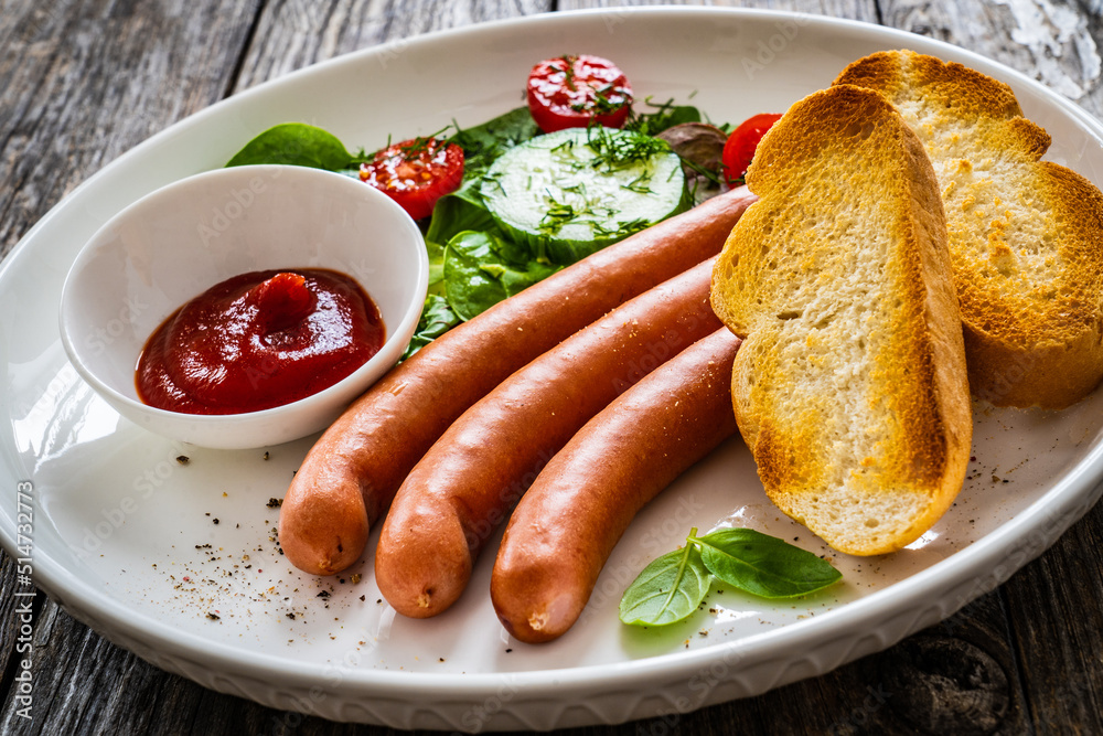 Breakfast - boiled sausages, bread and fresh vegetables served on wooden table
Breakfast - boiled sausages, bread and fresh vegetables served on wooden table