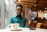 Portrait of handsome young black man in coffee shop looking at camera