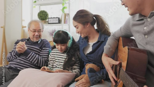 Father mother and daughter  and grand paretn teaching, playing guitar and learning musical notes at home. photo