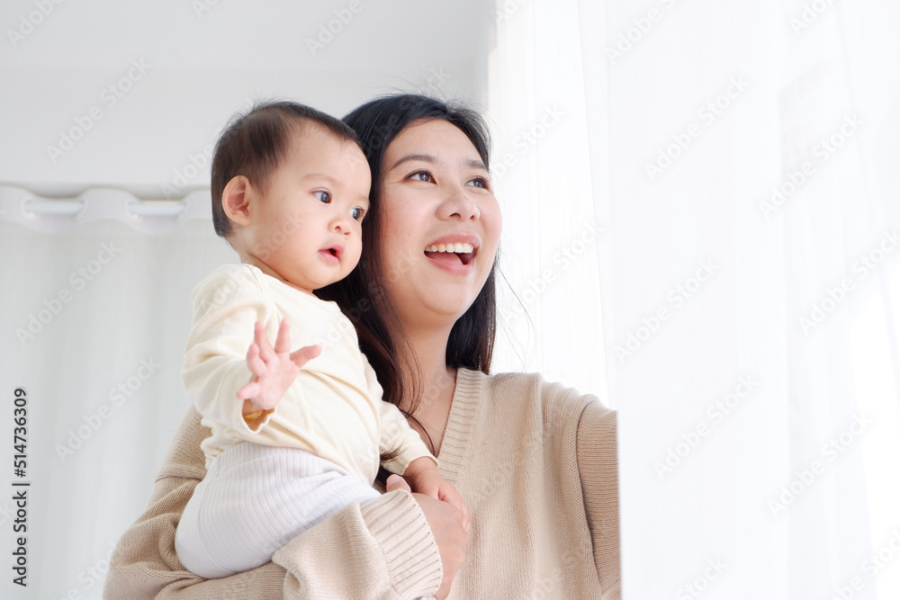 Mother holding a cute little boy with a happy smile. on the edge of the white curtain. Mother holding a cute little boy with a happy smile. on the edge of the white curtain.