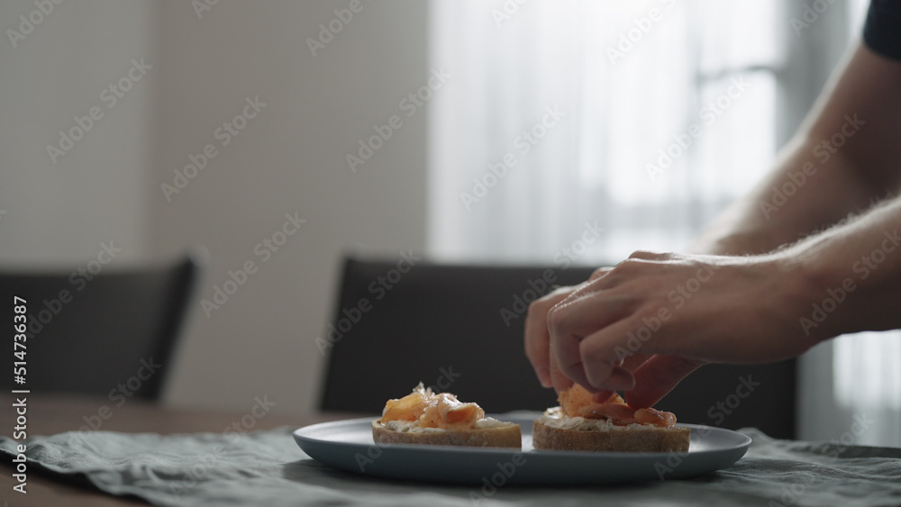 Man making bruschettas with cream cheese and smoked salmon
