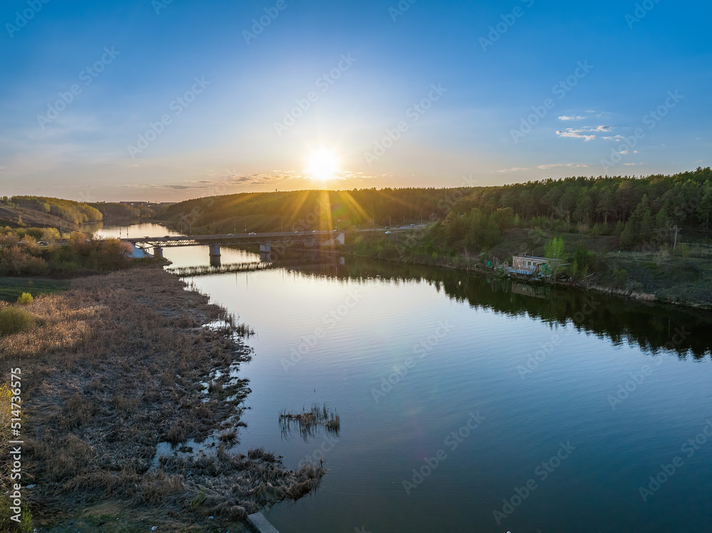 Obraz premium Beautiful view of the bridge across the Iset river in the city of Kamensk-Uralsky at sunset in spring. Kamensk-Uralskiy, Sverdlovsk region, Ural mountains, Russia.