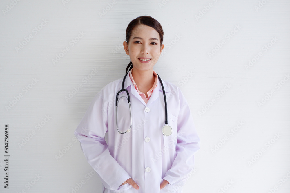 Asian female doctor standing and smiling with a stethoscope on the shoulder wearing a white medical uniform. Asian female doctor standing and smiling with a stethoscope on the shoulder wearing a white medical uniform.