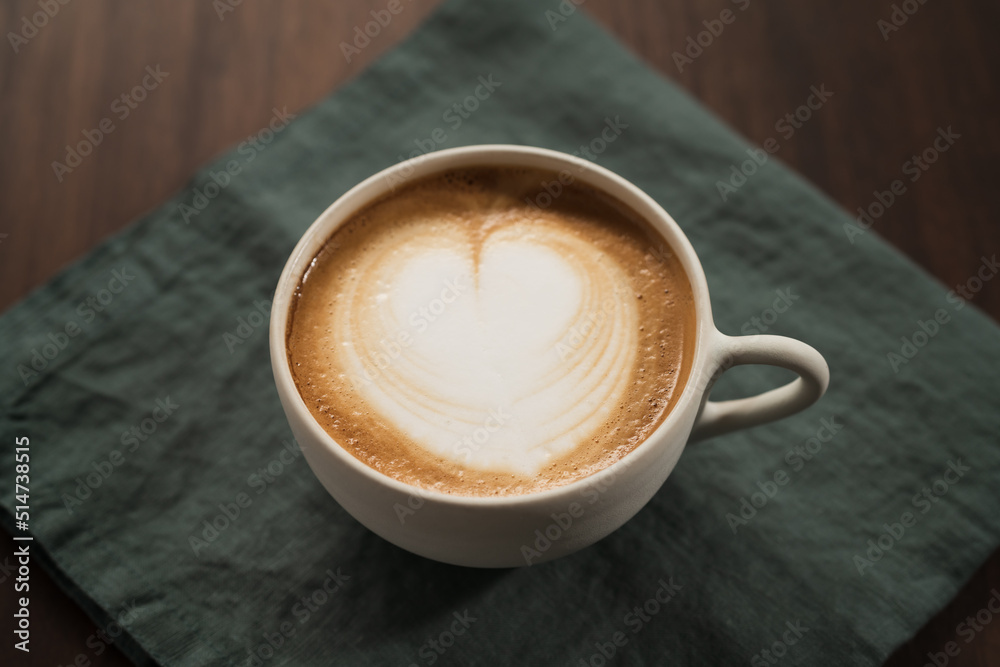Fresh flat white with latte art in ceramic cup on wood table