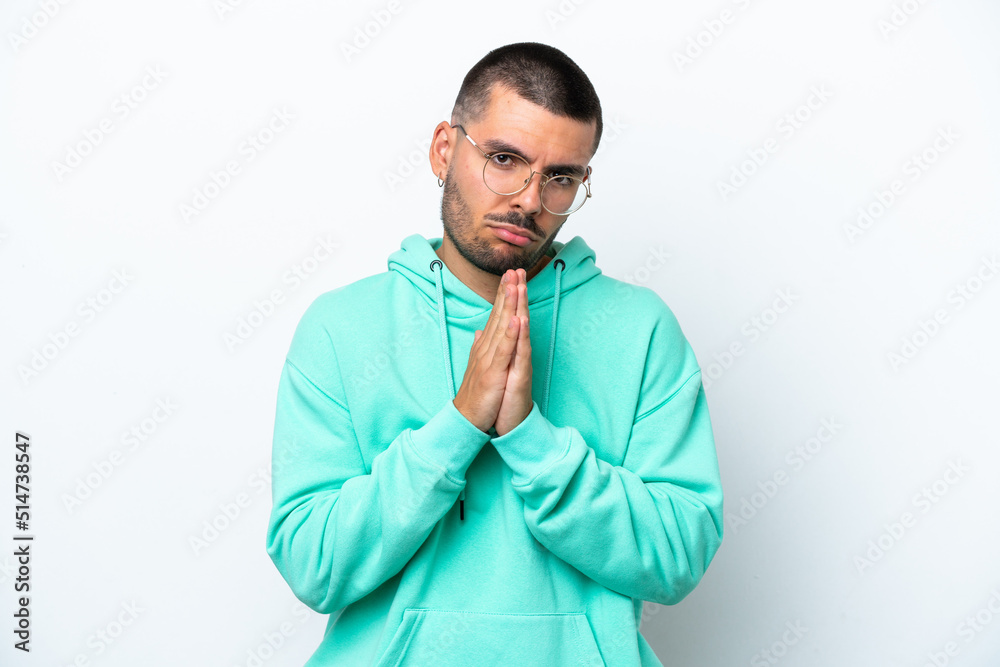 Young caucasian man isolated on white background keeps palm together. Person asks for something Young caucasian man isolated on white background keeps palm together. Person asks for something