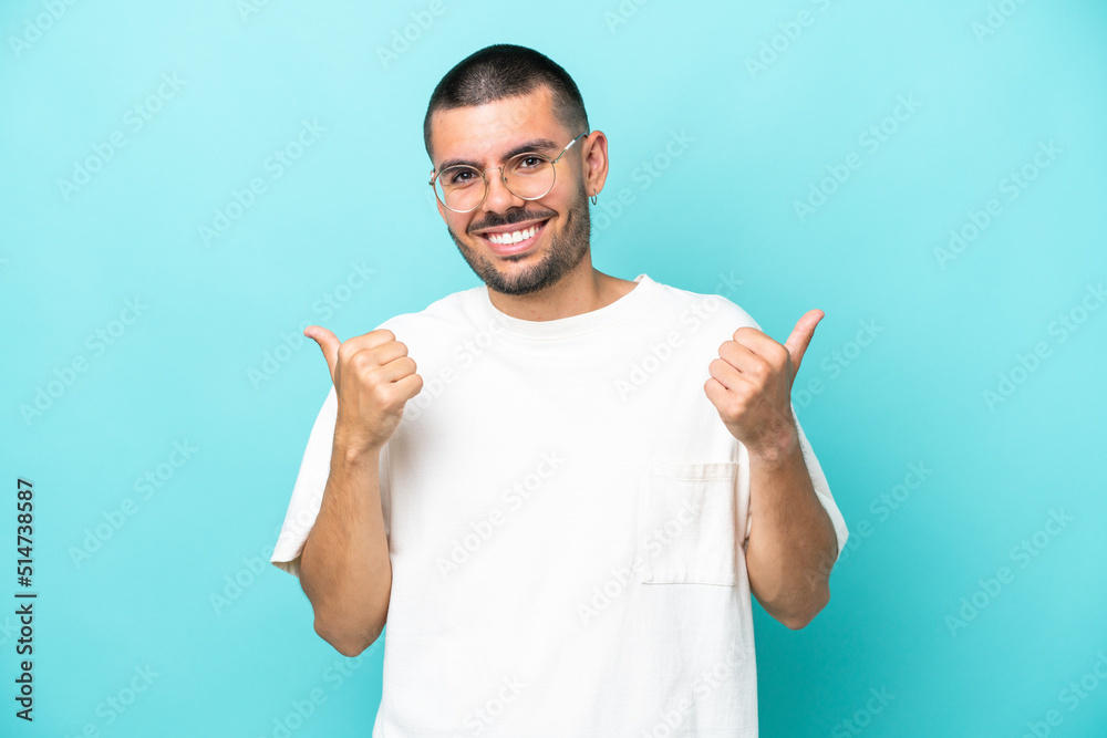 Young caucasian man isolated on blue background with thumbs up gesture and smiling Young caucasian man isolated on blue background with thumbs up gesture and smiling