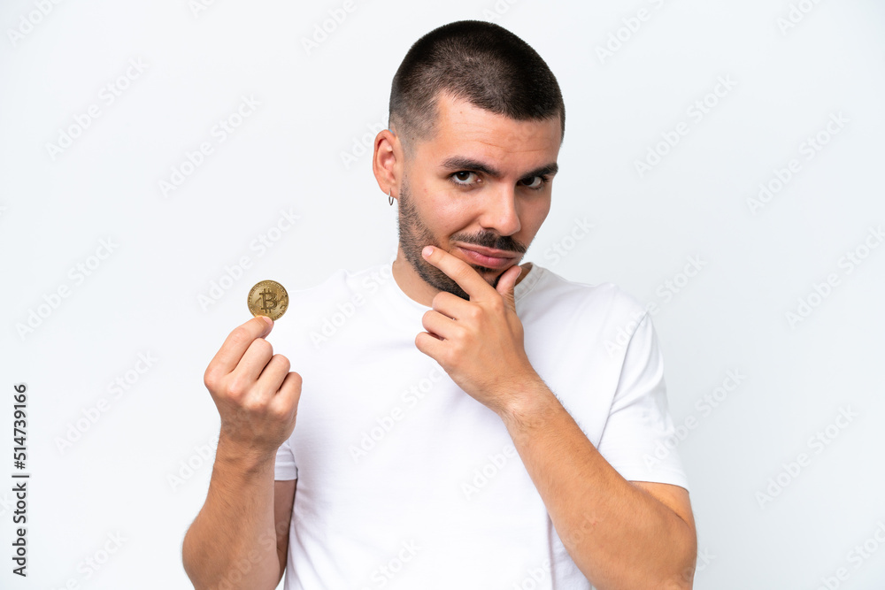 Young caucasian man holding a bitcoin isolated on white background thinking Young caucasian man holding a bitcoin isolated on white background thinking