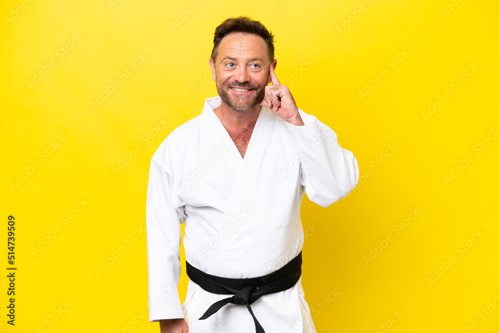 Middle age caucasian man doing karate isolated on yellow background thinking an idea while looking up