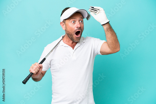 Middle age caucasian golfer player man isolated on blue background doing surprise gesture while looking to the side