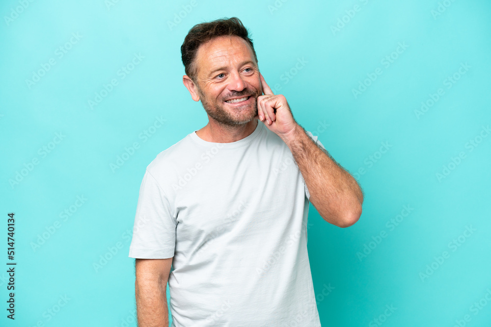 Middle age caucasian man isolated on blue background thinking an idea while looking up