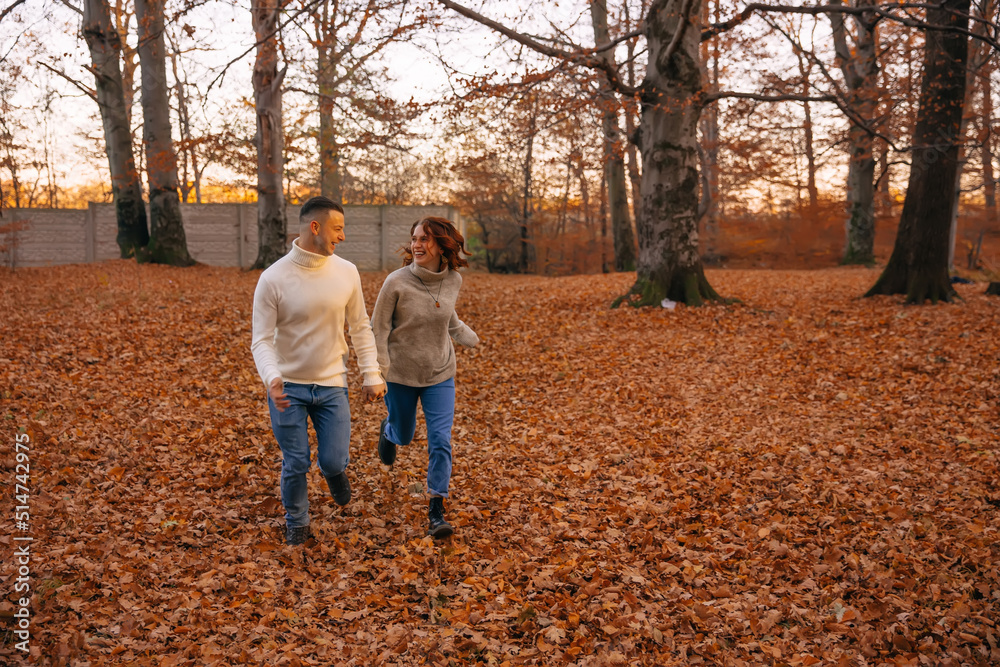 cheerful couple runs in the autumn park. covered with yellow foliage. Autumn walk in the fresh air. Two lovers in an autumn park. Romantic dates cheerful couple runs in the autumn park. covered with yellow foliage. Autumn walk in the fresh air. Two lovers in an autumn park. Romantic dates