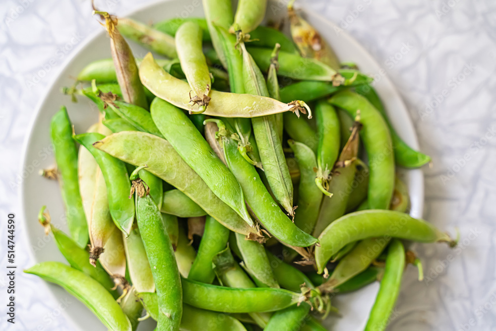 fresh green peas stacked in a bunch on a plate on a light background fresh green peas stacked in a bunch on a plate on a light background