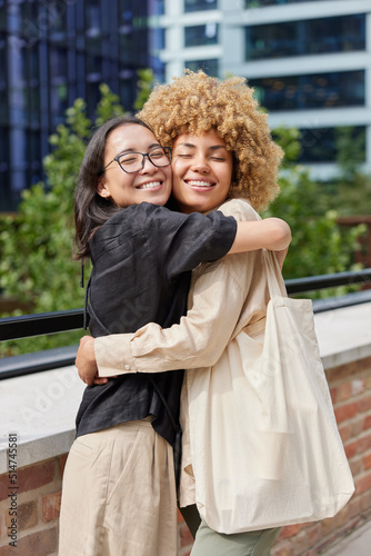 Happy best friends glad to meet together embrace each other on city street dressed in casual clothes have glad expressions show ultimate love and support. Friendship and relationship concept © wayhome.studio 