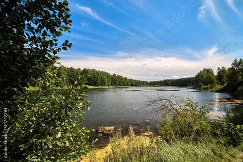 Beautiful lakeside view from a small lake in Russia, with lush green trees, blue sky and sunlight