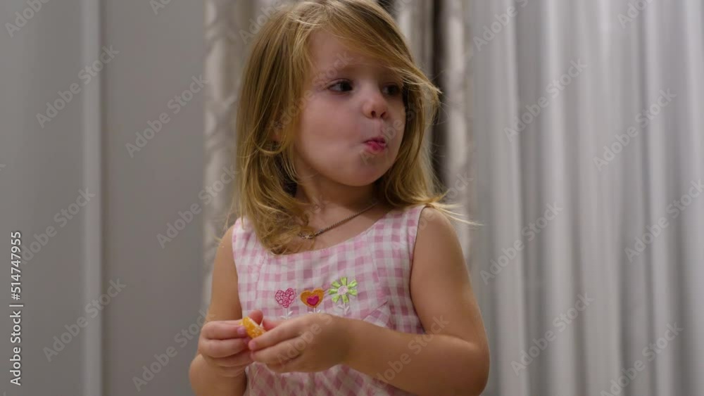 Little girl eating tangerine at kitchen table. Little girl eating tangerine at kitchen table.