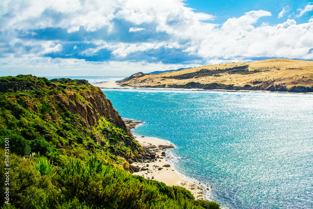 Rocky cliff and narrow sandy beach beneath it at the neck of Hokianga Harbour. Signal Station Track, Arai te Uru, Northland, New Zealand