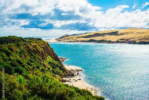 Rocky cliff and narrow sandy beach beneath it at the neck of Hokianga Harbour. Signal Station Track, Arai te Uru, Northland, New Zealand