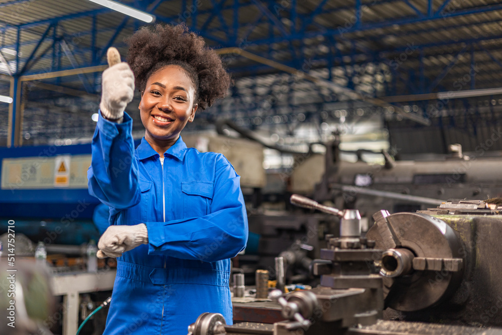 African American Young woman worker in protective uniform operating machine at factory Industrial.People working in industry.Portrait of Female Engineer looking camera at work place. African American Young woman worker in protective uniform operating machine at factory Industrial.People working in industry.Portrait of Female Engineer looking camera at work place.