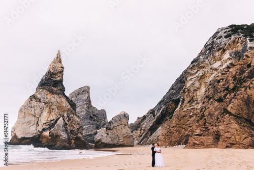 newlyweds hug on sandy beach near ocean on cliff background. bea