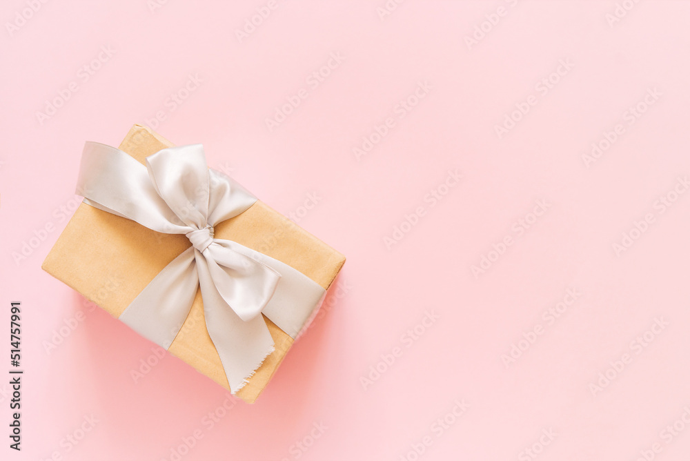 Gift box on pastel pink background. Birthday party, Valentines day or mother day greeting card. Top view, flat lay, copy space