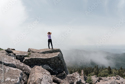 A girl on top of Mount Pidan looks at a beautiful mountain valley in the fog in summer. Travel and tourism. Hiking