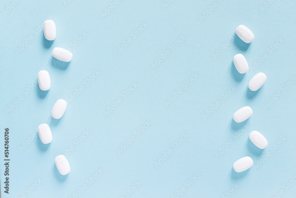 Scattered white pills on blue table. Mock up for special offers as advertising, web background or other ideas. Medical, pharmacy and healthcare concept. Copy space. Empty place for text or logo. Scattered white pills on blue table. Mock up for special offers as advertising, web background or other ideas. Medical, pharmacy and healthcare concept. Copy space. Empty place for text or logo.