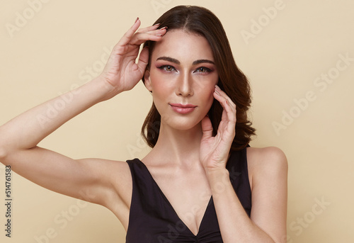 Face of the young pretty woman with a healthy skin. Pretty woman clean fresh skin isolated on nude color background.