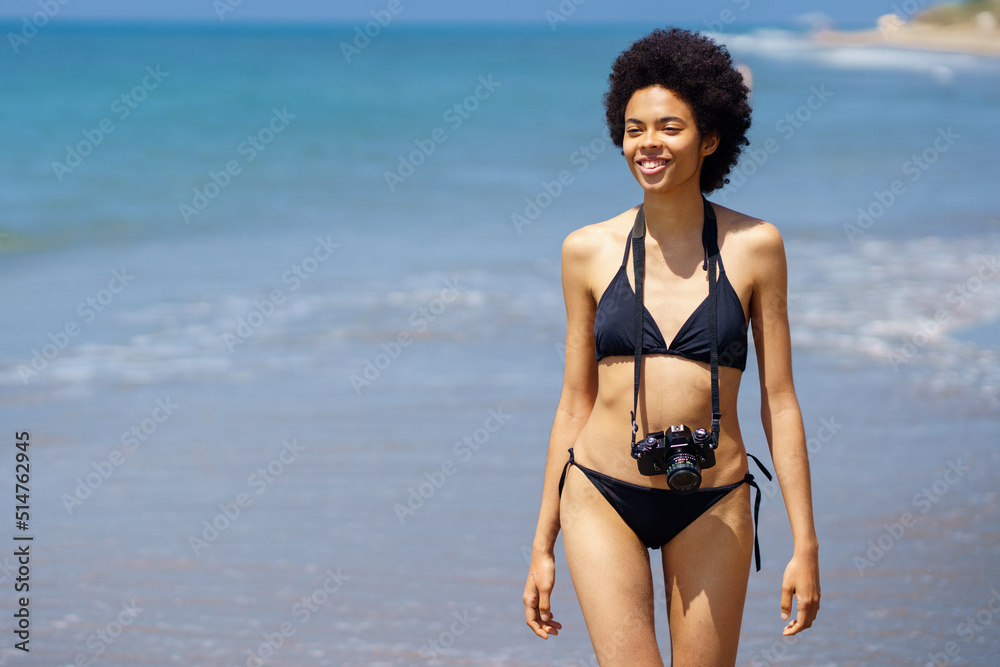 Joyful black woman with photo camera on wet coast Joyful black woman with photo camera on wet coast