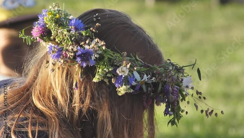 Wreath of flowers and oak leaves on the head. Celebration of the summer solstice in greenery. Midsummer celebration with oak wreath. Ligo holidays with weaving an oak wreath with your own hands.