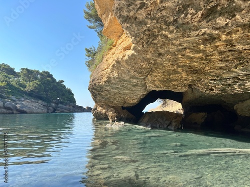 Beautiful island in the sea bay with turquoise clear water. Scenic sea cave grotto. Paradise beach in sunny summer day.