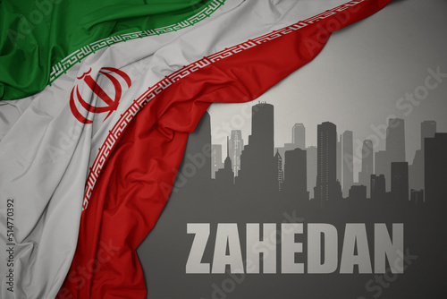 abstract silhouette of the city with text Zahedan near waving national flag of iran on a gray background.3D illustration photo