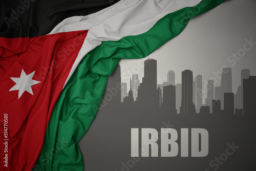 abstract silhouette of the city with text Irbid near waving national flag of jordan on a gray background.3D illustration photo