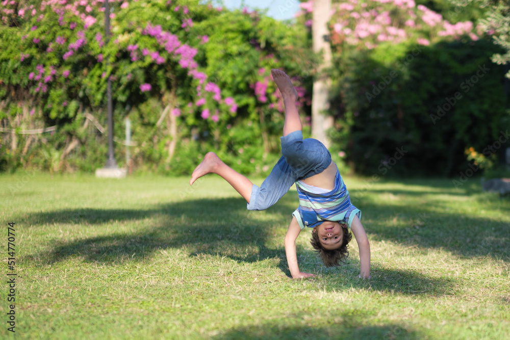 Mischievous preschooler boy somersaults on sand grass in the park. Mischievous preschooler boy somersaults on sand grass in the park.