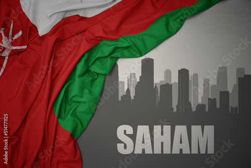 abstract silhouette of the city with text Saham near waving national flag of oman on a gray background.3D illustration