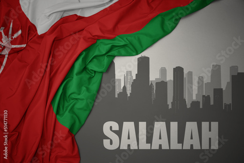 abstract silhouette of the city with text Salalah near waving national flag of oman on a gray background.3D illustration