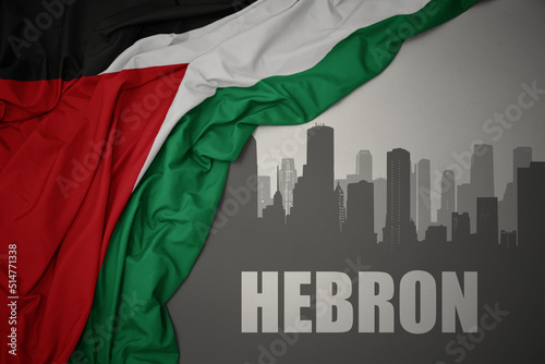 abstract silhouette of the city with text Hebron near waving national flag of palestine on a gray background.3D illustration