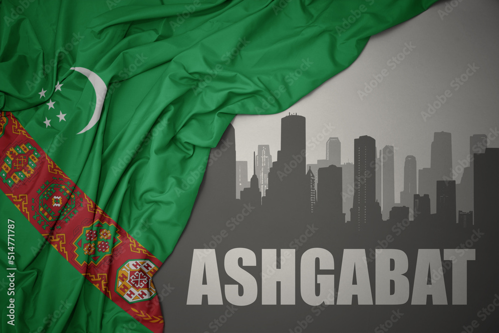 abstract silhouette of the city with text ashgabat near waving national flag of turkmenistan on a gray background.3D illustration