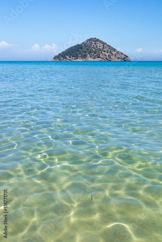 Shallow sea water surface with light reflection, little island in the background photo