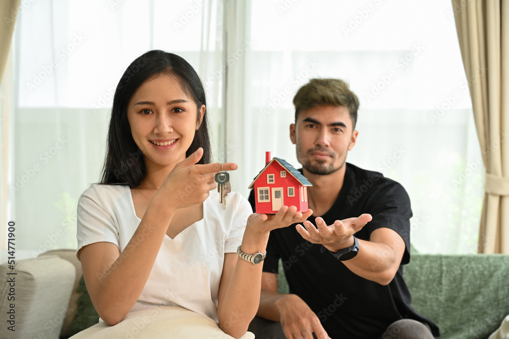 New house concept with happy young Asian couple holding small house model. New house concept with happy young Asian couple holding small house model.