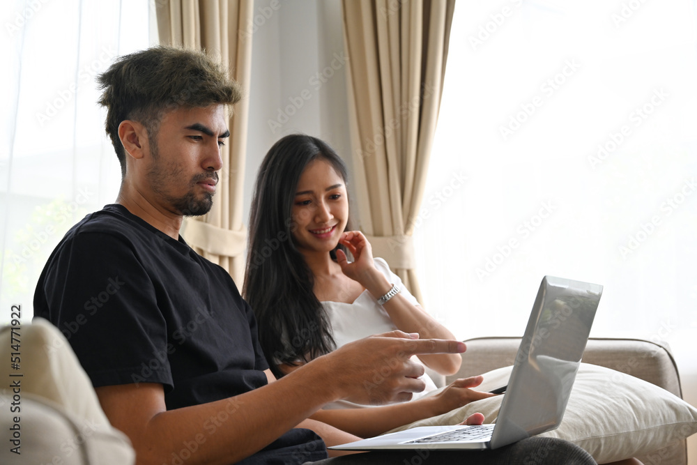 Asian couple sitting on couch while watching a movie on laptop, Domestic life and Domestic home concept. Asian couple sitting on couch while watching a movie on laptop, Domestic life and Domestic home concept.