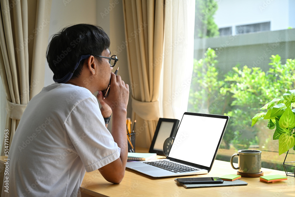 Handsome dark skinned man in casual clothes working laptop in living room, Blank screen of laptop, Domestic life concept. Handsome dark skinned man in casual clothes working laptop in living room, Blank screen of laptop, Domestic life concept.