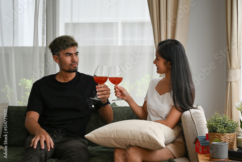 Young Asian couple clinking a glass of wine together with enjoy moment, Domestic life and Domestic home concept.