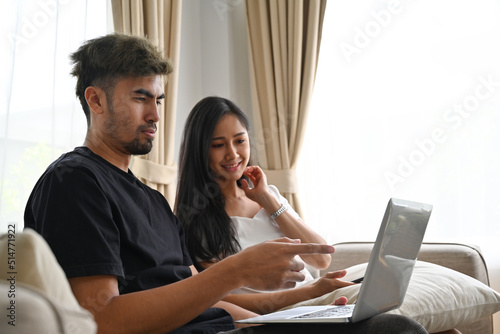 Asian couple sitting on couch while watching a movie on laptop, Domestic life and Domestic home concept.