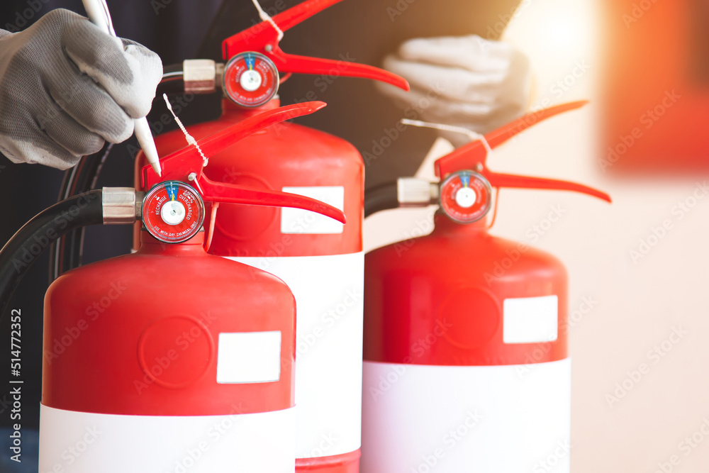 Obraz premium Close up fire extinguisher and firefighter checking pressure gauge level for protection and prevent and safety rescue and use of equipment on fire training concept.