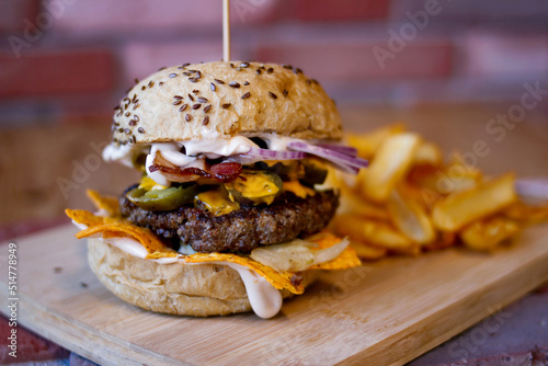 Burger w artystycznej kompozycji z frytkami i batatami oraz cebulą pieczarkami. Burgerownia - zdjęcie świeżego, apetycznego burgera photo