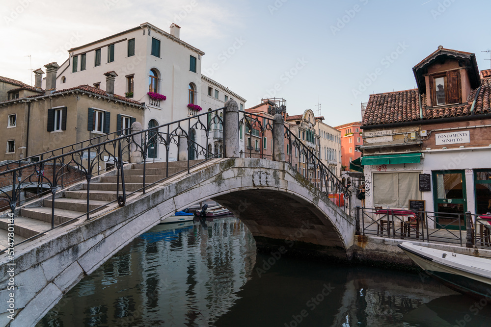 architectural detail of an old bridge in Venice, Italy over a canal and typical architecture on the background